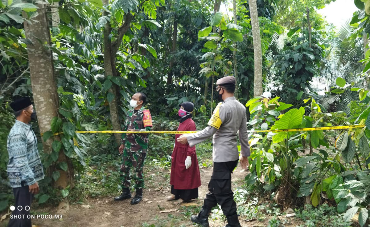 Petugas memasang garis polisi di lokasi penemuan mayat.
