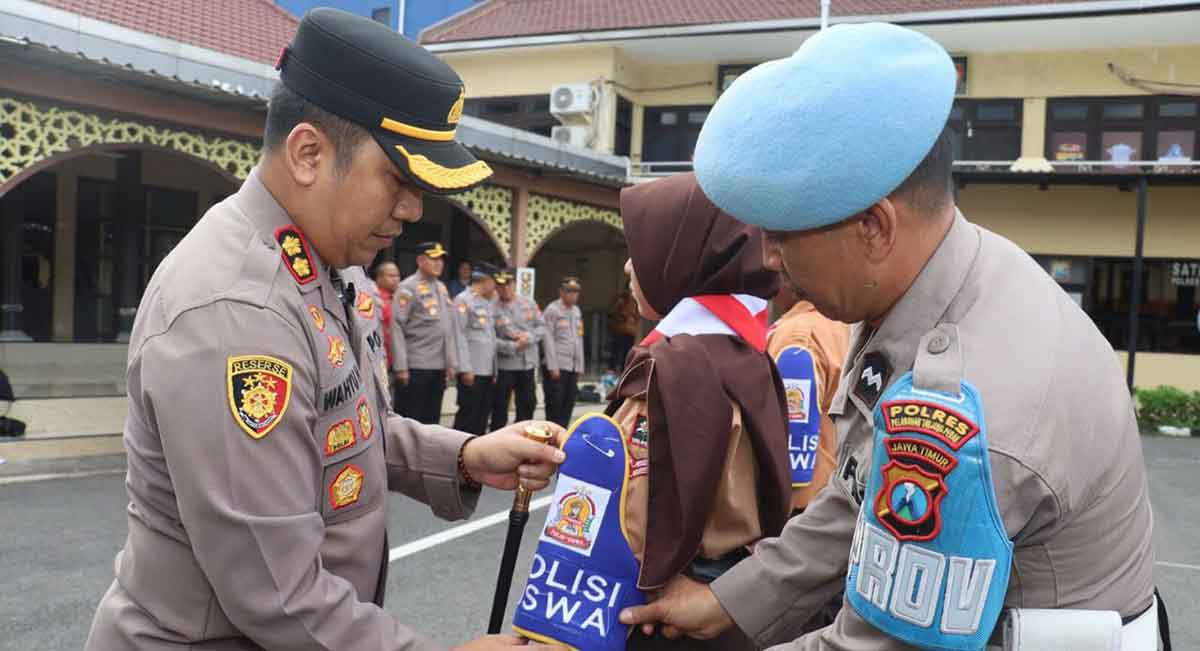 Kapolres Tanjung Perak saat memasangkan atribut kepada salah satu pelajar.
