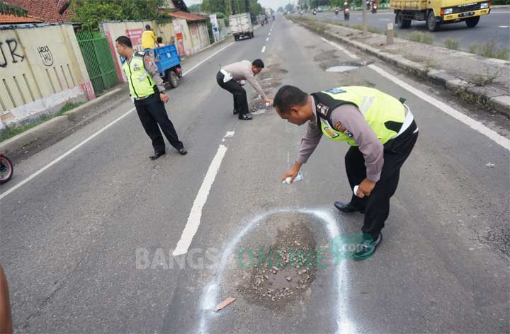 Polisi menandai lubang jalan dengan cat semprot. foto: RONY S/ BANGSAONLINE