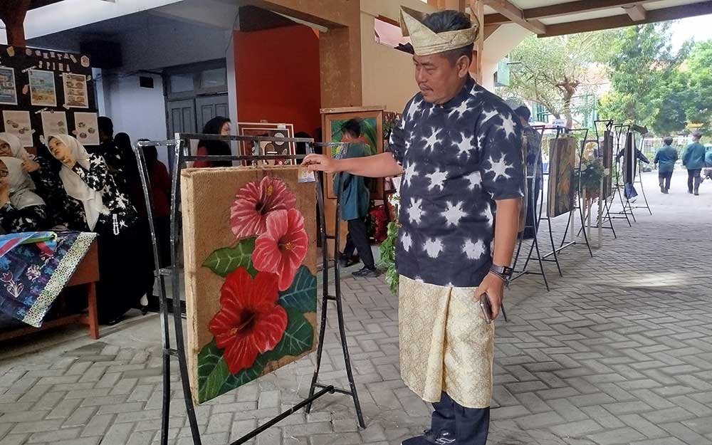 Kepala SMPN 1 Mojoagung, Yoni Trijoko Kurnianto, menunjukkan salah satu lukisan karya siswa. Foto: AAN AMRULLOH/ BANGSAONLINE