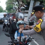 Petugas dari Satlantas Polres Blitar Kota saat membagikan helm serta cokelat ke salah satu pengendara pada Operasi Patuh Semeru 2025.