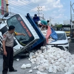 Truk muatan batu kapur yang terguling hingga menimpa sebuah mobil yang sedang terparkir