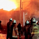 Petugas saat berusaha memadamkan kobaran api dalam gudang tiner yang terletak di Jalan Kalianak, Surabaya.