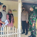 Pendamping PKH dan petugas gabungan TNI-Polri serta perangkat desa tengah menempelkan stiker di rumah KPM.