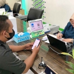 Petugas dari BPJS Kesehatan saat melayani salah satu peserta JKN di Gresik.