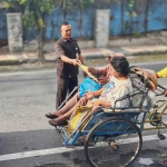 Eko Rahmanto, petugas keamanan di Kantor BPJS Kesehatan Cabang Madiun, saat membantu dua lansia yang ingin mendaftar program JKN.