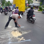 Petugas dari Satlantas Polres Blitar Kota saat memberikan penanda pada jalan rusak menggunakan cat semprot berwarna putih. 