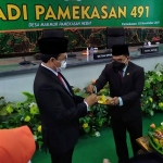 Ketua DPRD Pamekasan, Fathor Rahman, saat memberikan potongan tumpeng kepada Bupati Pamekasan, Baddrut Tamam, dalam sidang paripurna Hari Jadi Kabupaten Pamekasan ke-491.