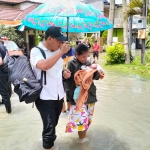 Camat Menganti Gunawan Purna Atmaja saat membantu evakuasi warganya dengan menggendong anak balita. Foto: SYUHUD/ BANGSAONLINE