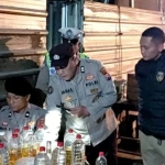 Anggota Polres Lamongan saat mengamankan barang bukti belasan botol miras jenis arak dari sebuah warung