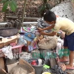 Anak Sujiono mengecek buku-buku sekolahnya yang basah akibat tumbahnya pohon yang menimpa rumah.