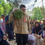 Bupati Kediri Hanindhito Himawan Pramana saat memanggul sayur kacang panjang pemberian petani. Foto: Ist.