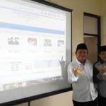 METAL: Paslon H Saiful Ilah-H Nur Ahmad Syaifuddin menunjukkan salam tiga jari, dengan latar belakang layar hasil hitung cepat, di Kantor DPC PKB Sidoarjo, Rabu (9/12/2015) sore. foto: musta