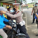 Petugas saat memasang masker pada tukang ojek di Blawi.
