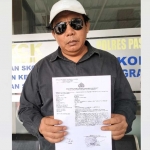 Kader PDIP di Kabupaten Pasuruan, Ruslan, ketika menunjukkan laporan polisi ke awak media.