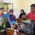 Seorang pegawai kafe inklusi di Tuban saat menata barang dagangannya.