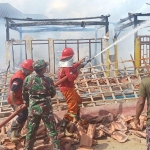 Petugas damkar saat melakukan pembasahan puing-puing bangunan yang luluh lantak usai terbakar.