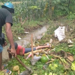 Sugiarto, Petugas PU Provinsi bersama temannya sedang membersikan saluran air yang belum dibuat drainase. Foto: GANDA S/BANGSAONLINE