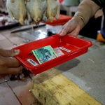 Para pembeli dan penjual yang sedang bertransaksi menggunakan nampan sebagai perantara pembayaran di Pasar Genteng Baru. foto: ist.