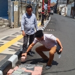 Ketua Komisi III DPRD Gresik Sulisno Irbansyah bersama Sekretaris Abdullah Hamdi menutup saluran yang penutupnya hilang dengan batu bata. Foto: SYUHUD/ BANGSAONLINE