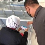 Pegawai BPJS cabang Gresik saat membantu peserta JKN menggunakan aplikasi Mobile JKN. (Ist)
