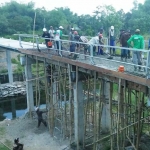 Warga gotong royong membangun jembatan di atas sungai Konto Desa Pucangsimo.  foto: RONY/ BANGSAONLINE