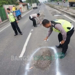 Polisi menandai lubang jalan dengan cat semprot. foto: RONY S/ BANGSAONLINE