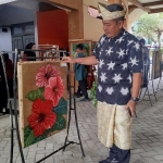 Kepala SMPN 1 Mojoagung, Yoni Trijoko Kurnianto, menunjukkan salah satu lukisan karya siswa. Foto: AAN AMRULLOH/ BANGSAONLINE
