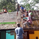 Warga dan petugas BPBD Blitar saat memperbaiki salah satu atap rumah warga.