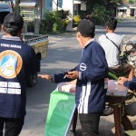 Anggota Karang Taruna Desa Gondang, Kecamatan Plosoklaten, Kabupaten Kediri saat membagikan nasi bungkus kepada para pengguna jalan. (foto: ist)