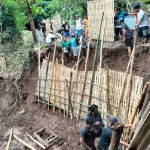 Tim BPBD Kabupaten Madiun bersama relawan dan warga memasang dindin anyaman bambu di area pemakaman yang longsor diterjang banjir