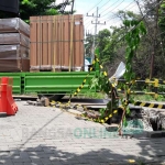 Kendaraan berat melintas di tepi jembatan yang ambrol. foto: SYUHUD/ BANGSAONLINE