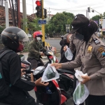 Petugas Polresta Banyuwangi saat membagikan nasi, air, dan masker kepada pengguna jalan