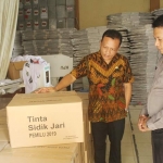 Petugas KPU Kabupaten Jombang bersama Polisi saat memeriksa kemasan logistik tinta sidik jari yang datang.