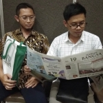 Kasubbid Advokasi dan KIE BKKBN Prov Jatim Toma Afriandi, SH MSi, sedang membaca koran HARIAN BANGSA, ditermani Staf Audio Visual Adetya Surya Y., AMd,. Foto: YUDI ARIANTO/BANGSAONLINE