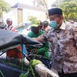 Bupati Fadeli saat membagikan sembako dan masker kepada tukang becak yang melintas di Jalan Lamongrejo. foto: NUR QOMAR/ BANGSAONLINE