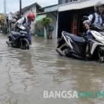 HARUS TURUN: Sejumlah siswa mematikan mesin motornya saat melintasi banjir yang merendam jalan Kelurahan Sidokare Kecamatan Kota Sidoarjo, Senin (10/10). foto: MUSTAIN/ BANGSAONLINE