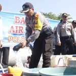 Wakapolres Ngawi Kompol Hartono saat mengisi bak air milik warga yang sudah diantrekan.