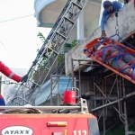 Petugas dari DPKP Surabaya saat mengevakuasi pekerja bangunan yang pingsan.