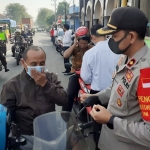 Wakapolres Pasuruan Kompol Muhammad Haris sedang memasang masker pada salah seorang pengguna jalan.