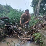 Wakil Bupati Magetan Kang Suyat turun langsung membersihkan sumbatan sampah di selokan saat meninjau banjir di Ngariboyo. Foto: ANTON/HB
