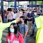 Para penumpang yang baru saja turun dari bus di Terminal Purabaya dilakukan screening suhu tubuh.