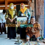 Wakil Bupati Gresik, Aminatun Habibah, saat menunjukkan lukisan yang dibelinya dari Aam, pelukis difabel. Foto: SYUHUD/BANGSAONLINE