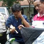 Kanit Reskrim Kenjeran menenteng jimat milik pelaku. Foto:rusmiyanto/BANGSAONLINE