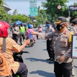 Kabag Ops Polres Kediri Kota, Kompol Abraham Sisik saat ikut membagikan masker kepada pengguna jalan. foto: Muji Harjita/ BANGSAONLINE.com