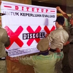 Petugas Satpol PP Blitar memasang plakat "Disegel" pada salah satu karaoke yang ditutup di Blitar. foto: AKINA/ BANGSAONLINE