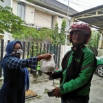 Umi Tutut, bagian pemasaran HARIAN BANGSA menyerahkan sedekah rutin HARIAN BANGSA kepada ojek online di depan kantor HARIAN BANGSA Jalan Gayungsari Surabaya, Jumat (3/4/2020). foto: BANGSAONLINE.COM  