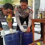Petugas menunjukkan barang bukti miras yang berhasil disita. foto: AKINA/ BANGSAONLINE