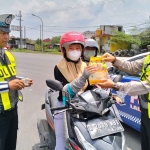 Kanit Turjawali Satlantas Polres Pasuruan, Ipda Hendik Arianto, saat memberikan sembako kepada salah satu pengendara yang tertib berlalu lintas.