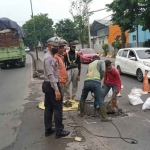 Petugas dari Satlantas Polres Pasuruan saat menambal sulam jalan berlubang.